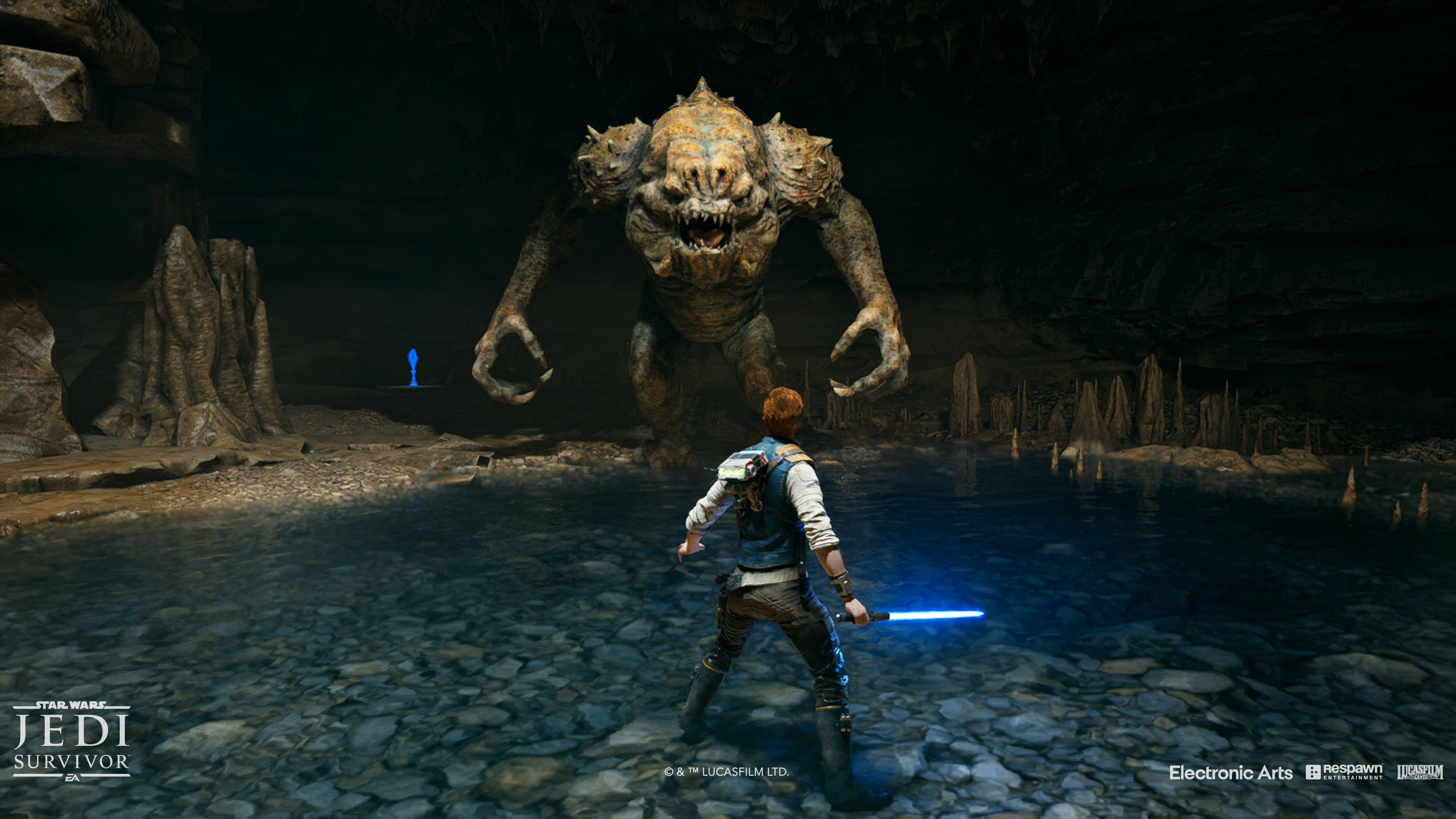 Figur mit blauem Lichtschwert steht einem großen Monster in dunkler Höhle gegenüber. Szene aus Videospiel.