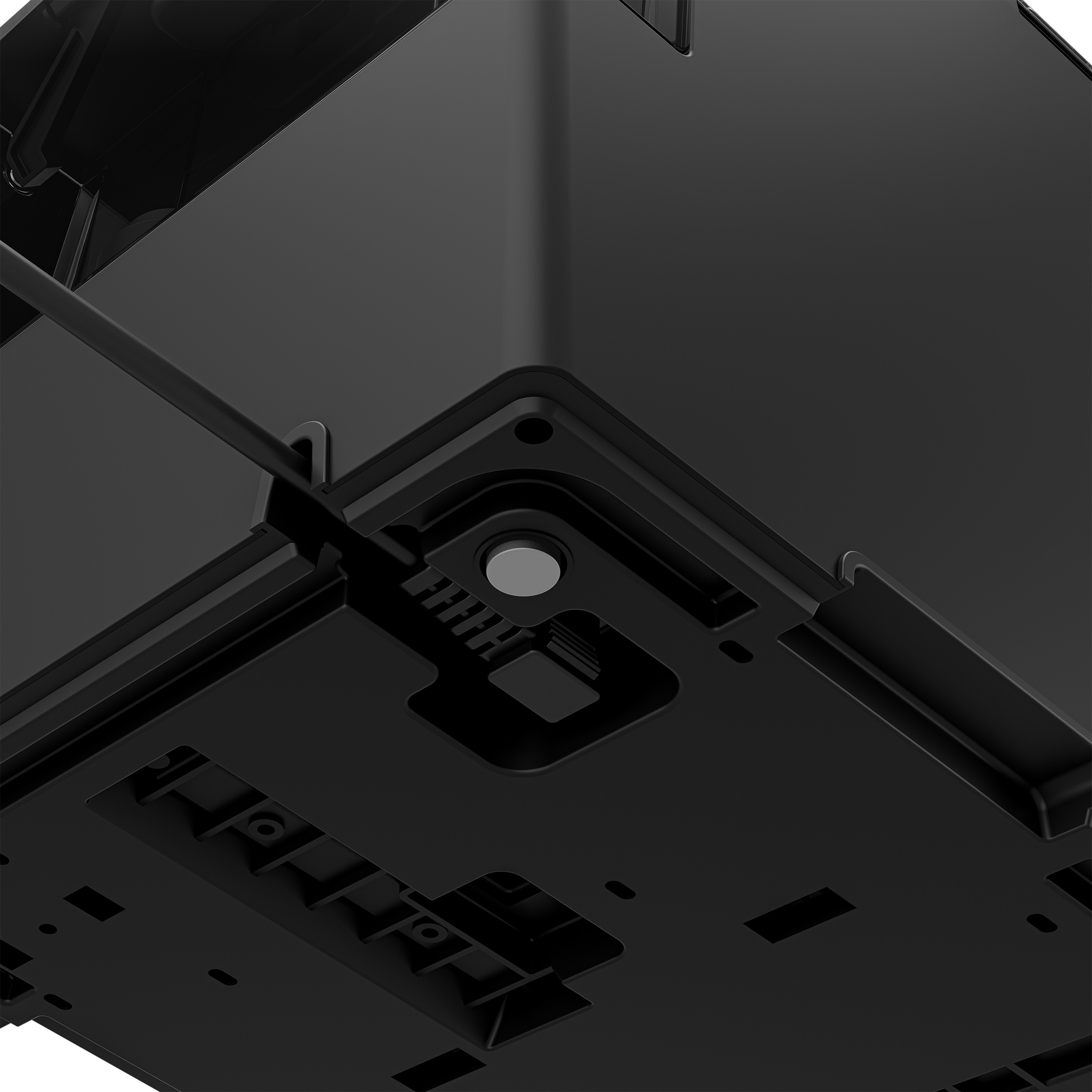 Widok od dołu czarnego urządzenia elektronicznego z wpuszczonym przyciskiem i szczegółowym designem.