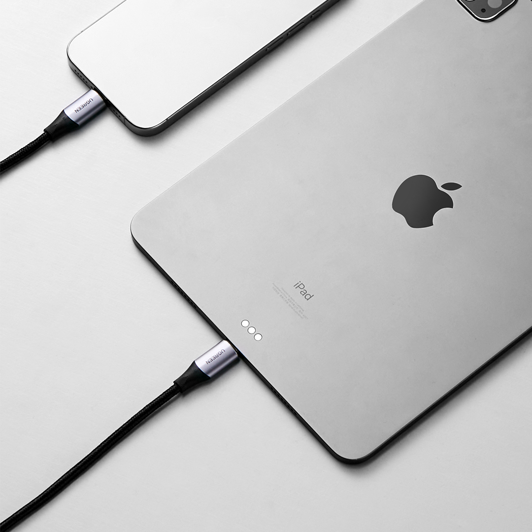 Bir telefona bağlı siyah bir UGREEN kablosuyla şarj edilen gümüş renkli bir iPad.