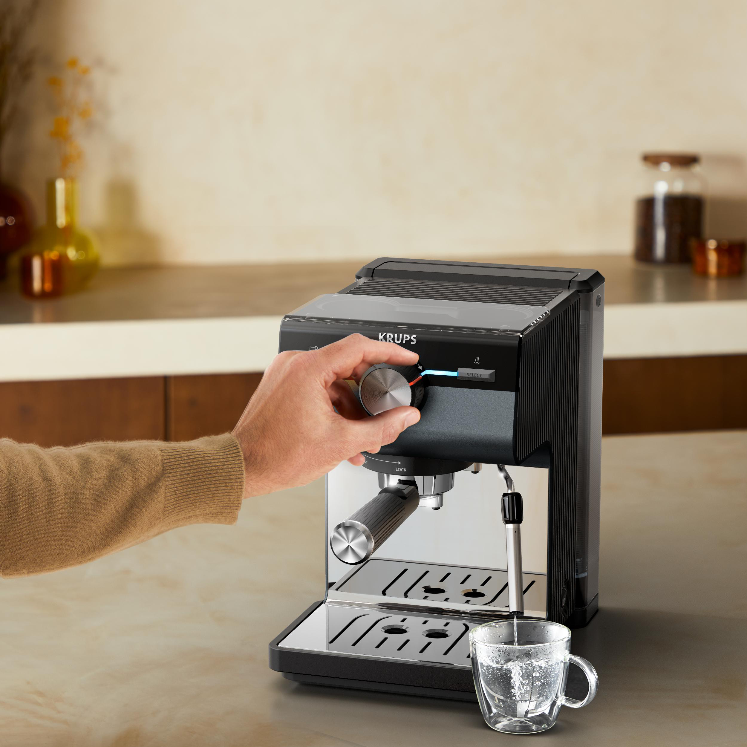 Espressomaschine auf Arbeitsplatte. Eine Hand dreht am Drehregler.