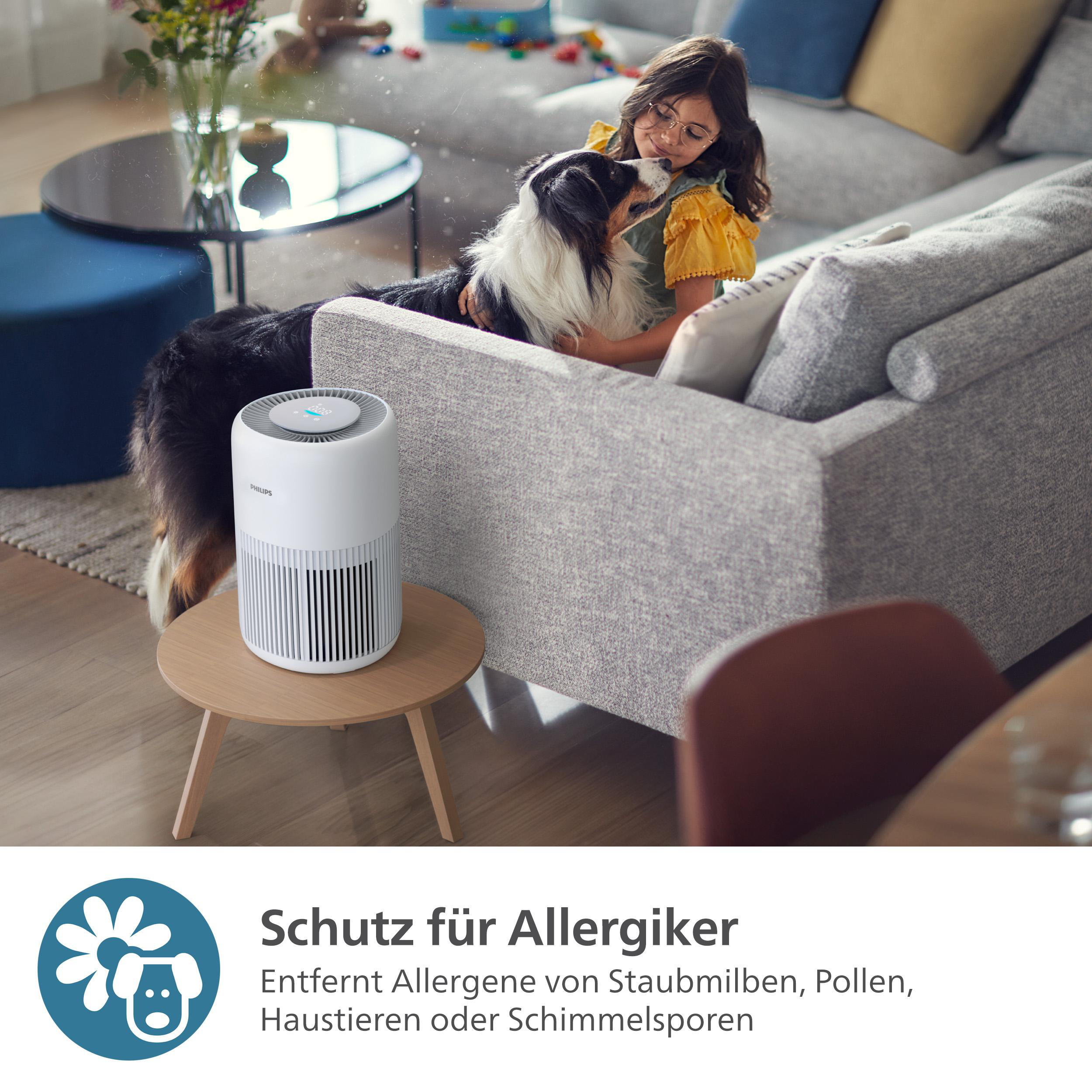 Ein Mädchen und ein Hund auf Couch, Philips Luftreiniger auf kleinem Tisch.