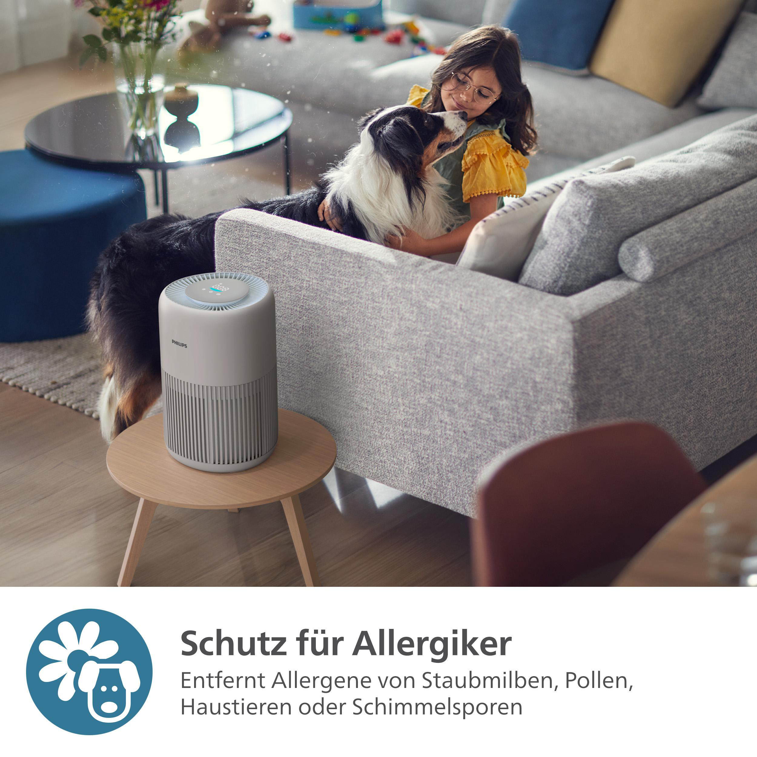 Ein Luftreiniger neben einem Sofa mit einem Hund und einem Mädchen.