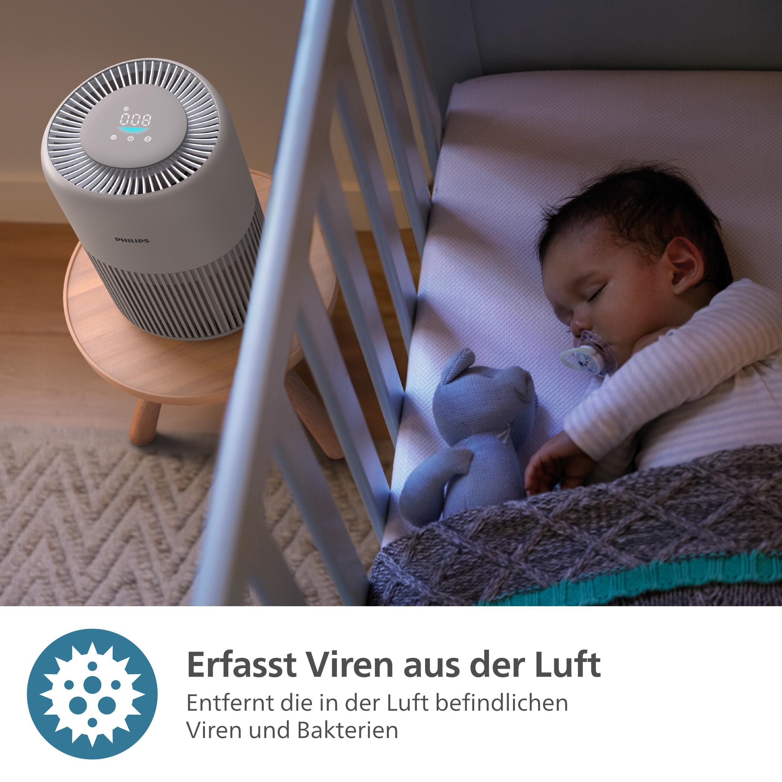 Ein Baby schläft in einem Kinderbett mit einem Luftreiniger auf einem Ständer in der Nähe. Text über Luftreinigung.