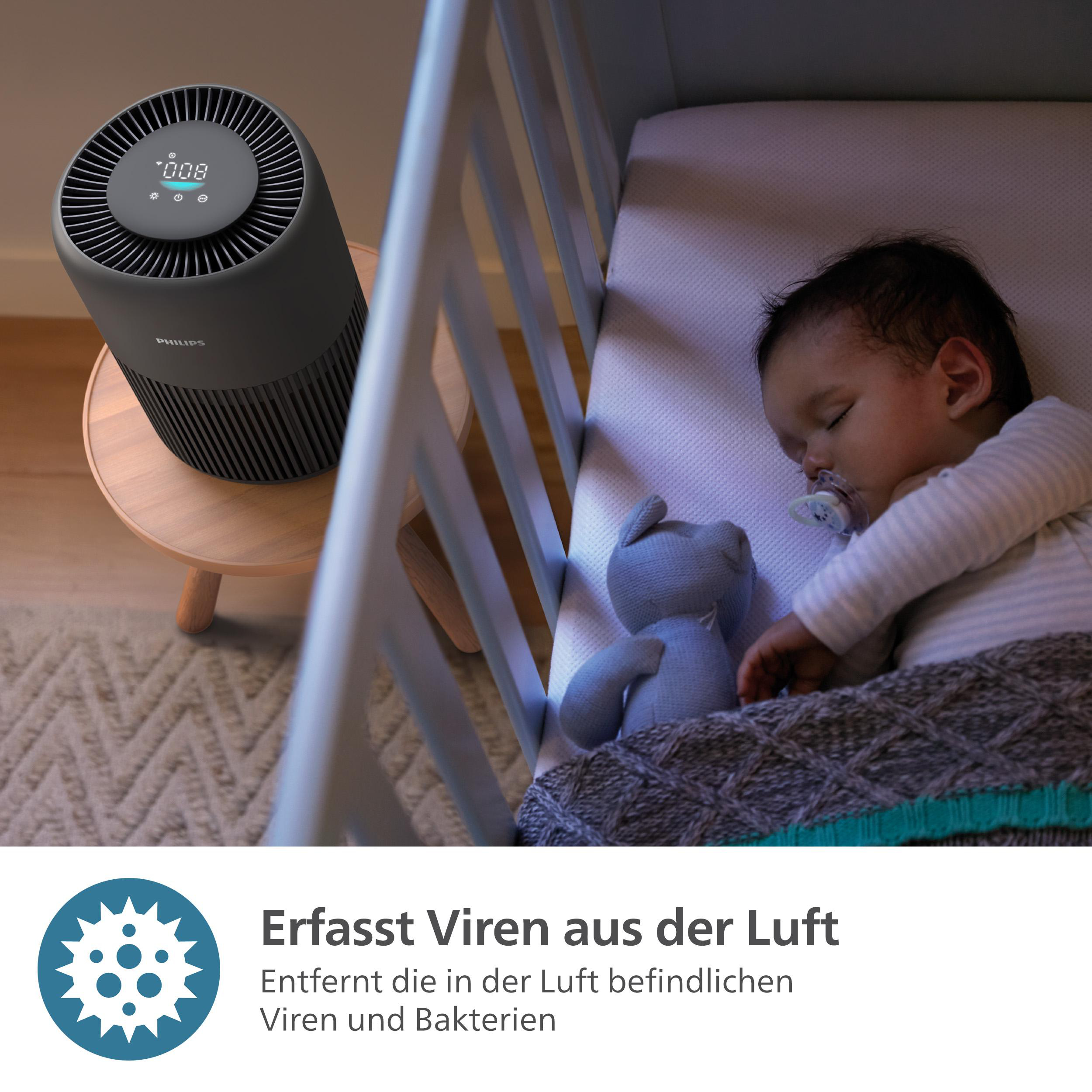 Baby schläft in Krippe, Luftreiniger daneben.