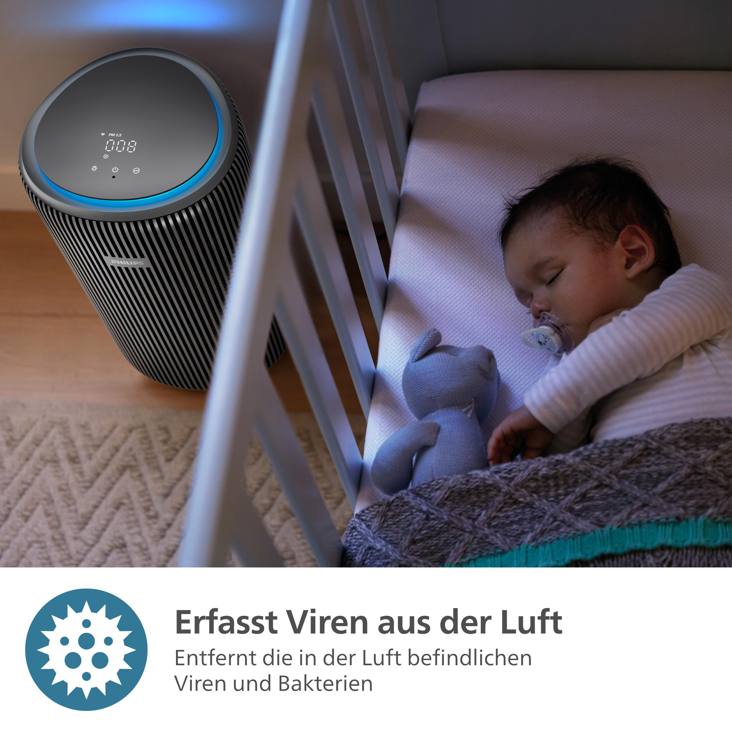 Baby schläft im Kinderbett. Ein Luftreiniger steht daneben. Ein blaues Stofftier liegt neben dem Baby.