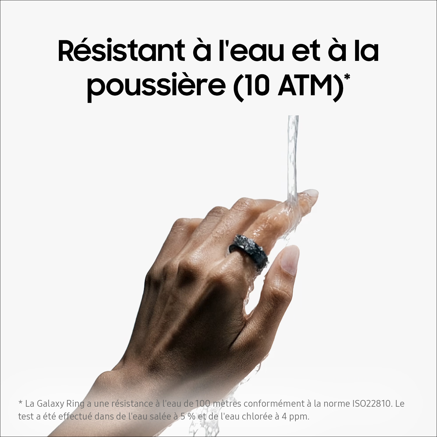 Une main portant une bague noire sous l'eau courante sur fond blanc.
