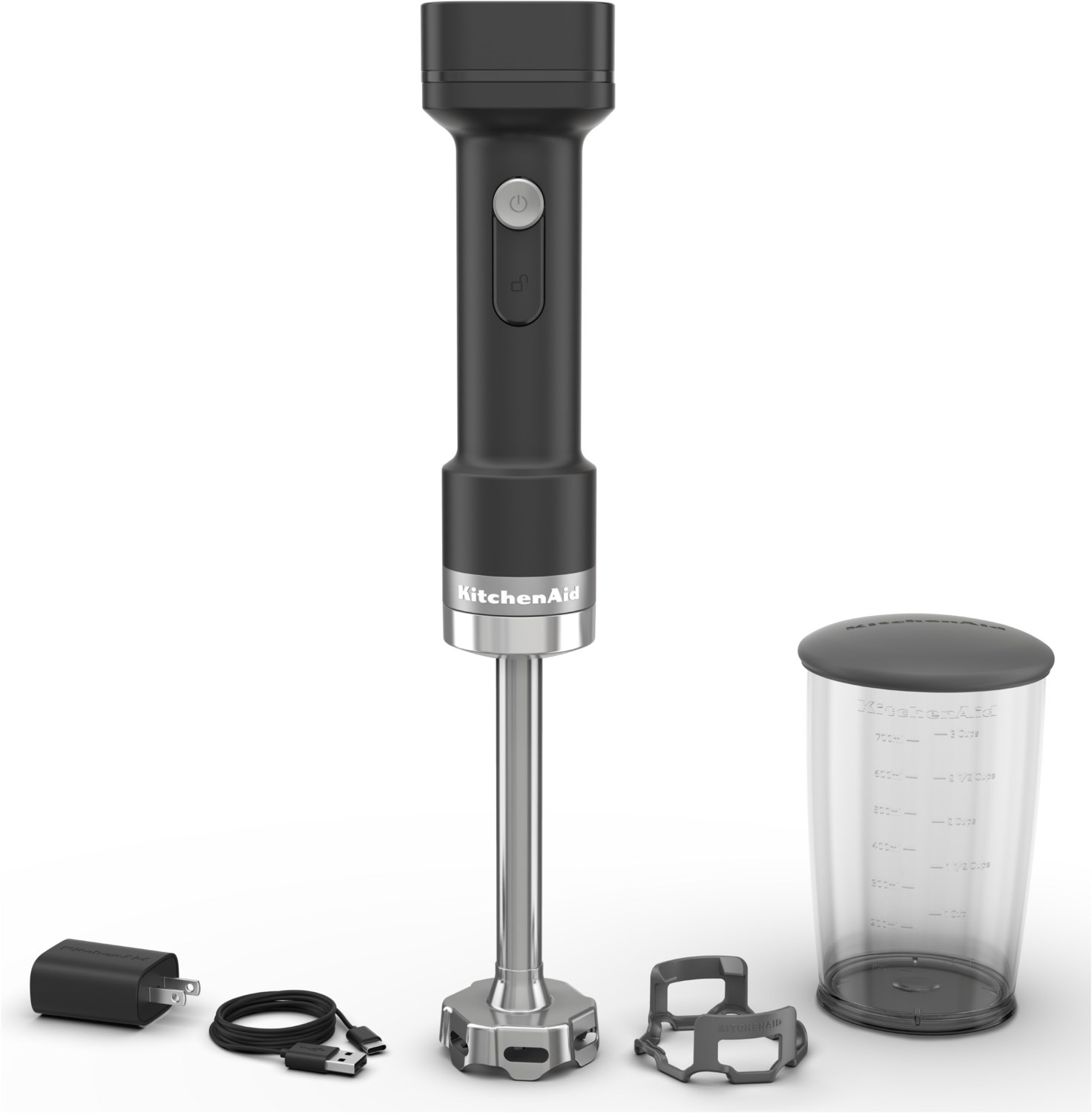 Fekete KitchenAid kézi mixer, töltő és kiegészítők fehér háttér előtt.