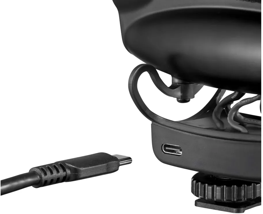 Gros plan sur un microphone noir avec un câble USB-C connecté. Le fond est flou.