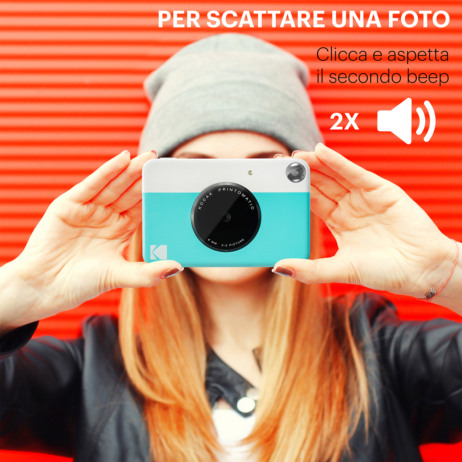 Persona che tiene una fotocamera istantanea turchese e bianca, sfondo rosso.