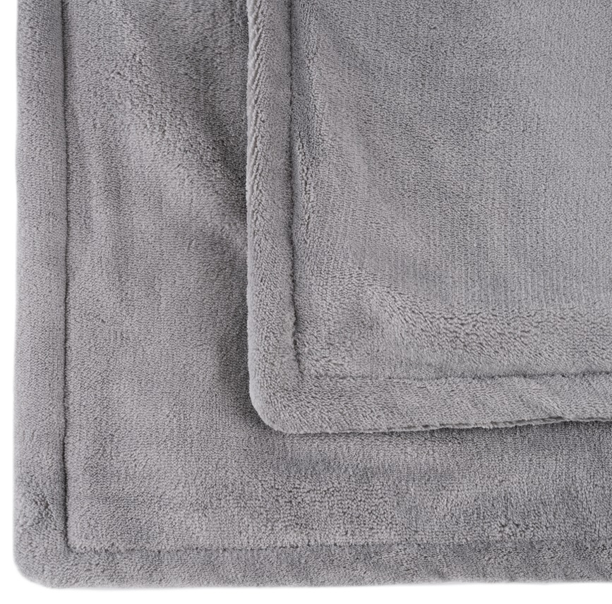 Zbliżenie miękkiego, szarego koca, z widocznym szwem na krawędziach złożonej tkaniny.