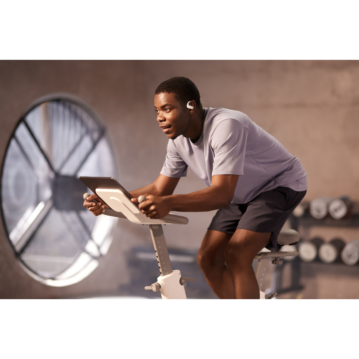 Homme sur un vélo d'exercice portant des écouteurs, dans une salle de sport.