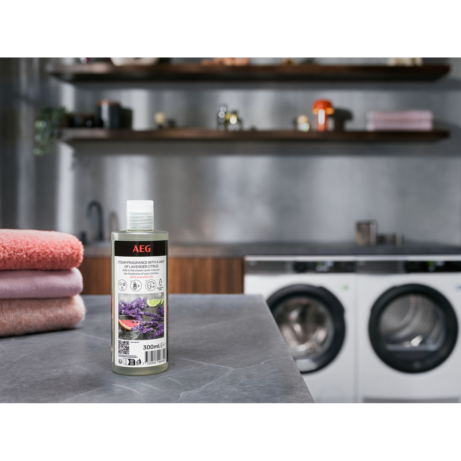 Bouteille de parfum de lessive AEG sur un comptoir, avec des serviettes et des machines à laver en arrière-plan.