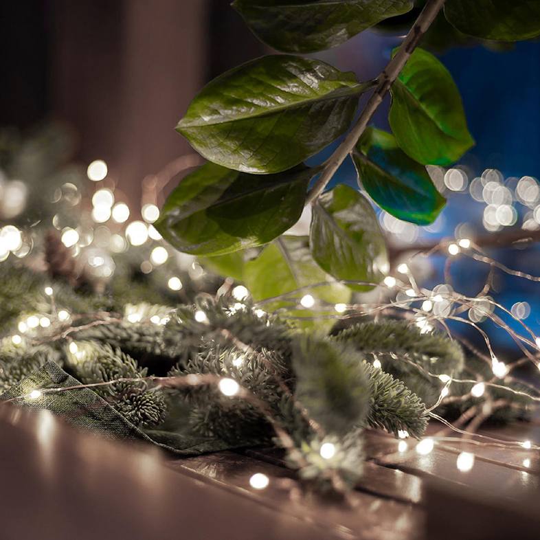 Karácsonyi fények és lombozat fa felületen, bokeh a háttérben.