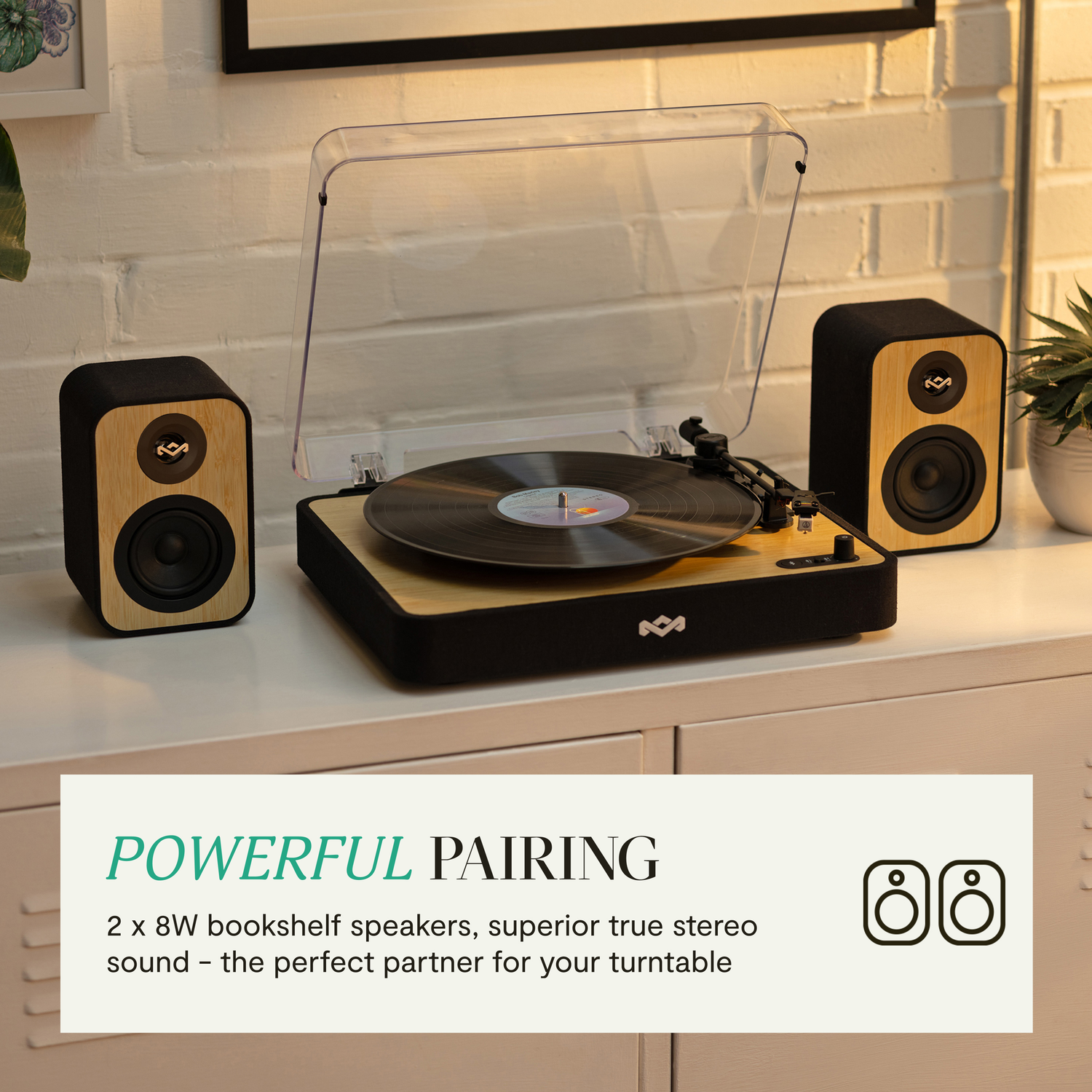 Platenspeler met luidsprekers op een witte kast. Tekst: 'POWERFUL PAIRING'.
