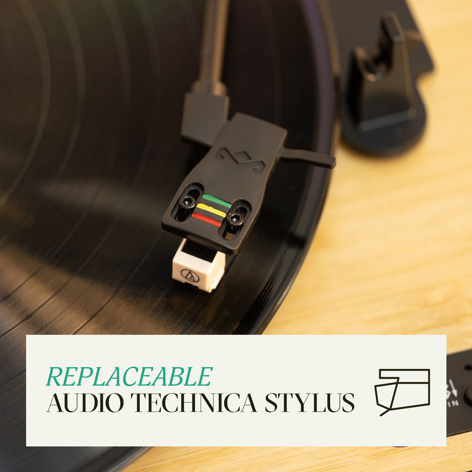 Close-up van een platenspeler stylus op een vinylplaat. Tekst: VERVANGBARE AUDIO TECHNICA STYLUS.