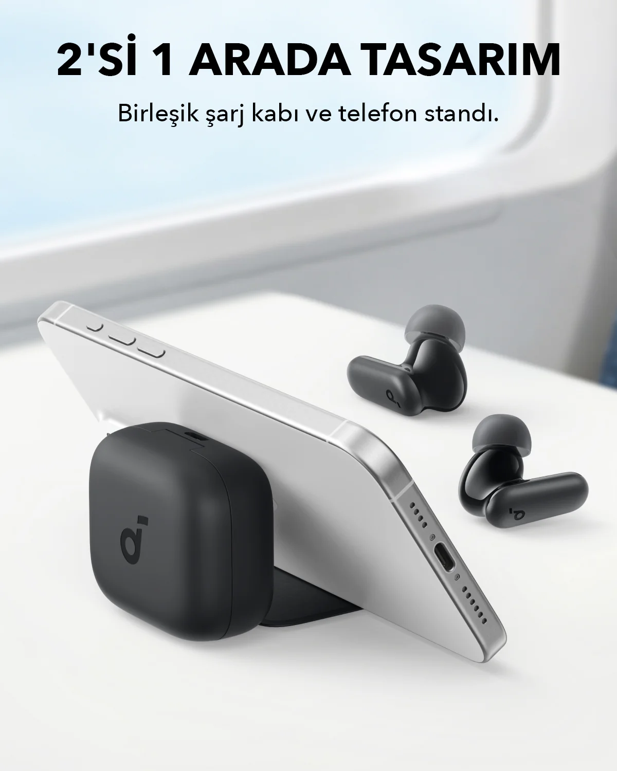 Bir stand üzerinde bir telefon, yakınlarda kulaklıklar, telefonun yanında siyah bir şarj tabanı.
