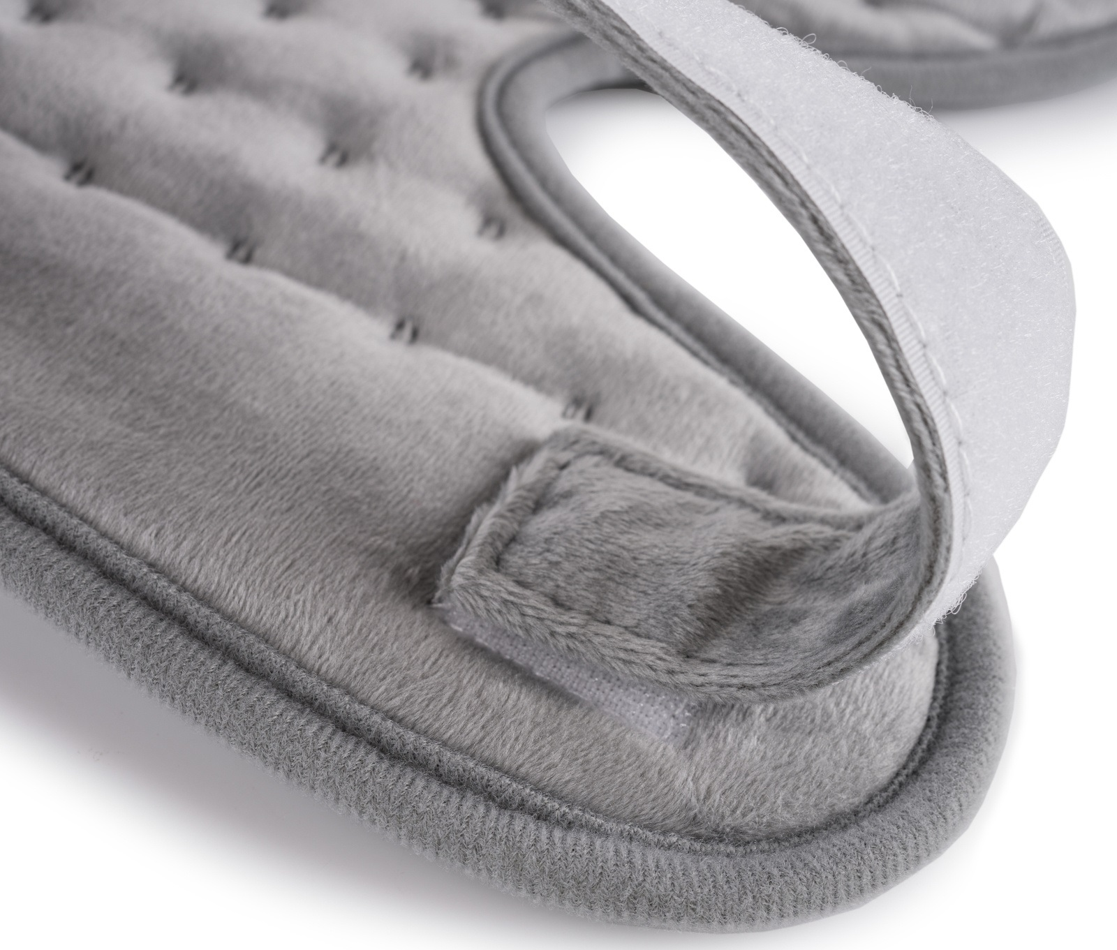 Zbliżenie szarej poduszki grzewczej z paskiem na rzep. Ma teksturowaną powierzchnię i miękką krawędź.