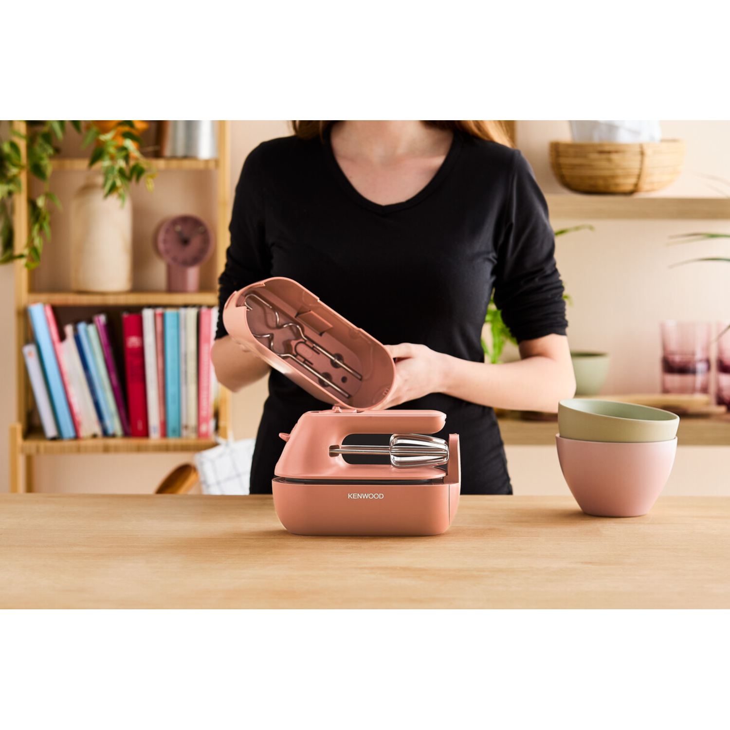 Woman holding an open pink hand mixer case. Mixer and attachments are visible inside.