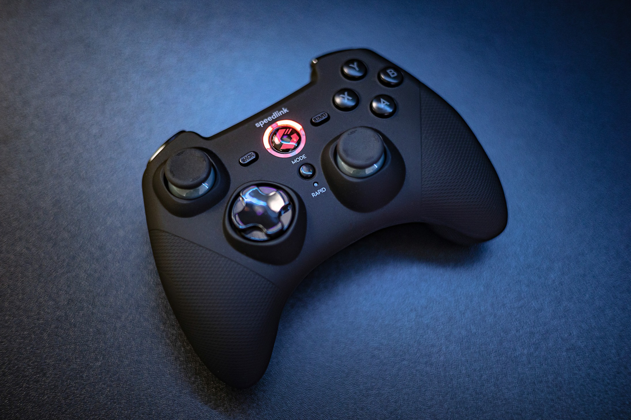 Schwarzes Gamepad auf blauer Oberfläche, beleuchtete Tasten.