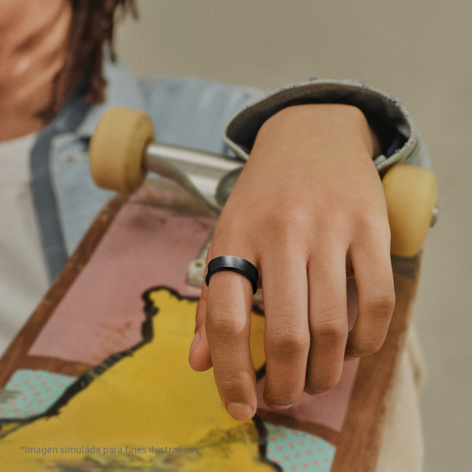 Mano de persona con un anillo negro, sosteniendo una patineta.
