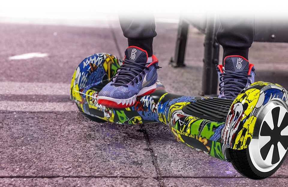 Graffiti kaplı bir hoverboard'da, spor ayakkabısı giyen, bir kaldırımda bir kişi.