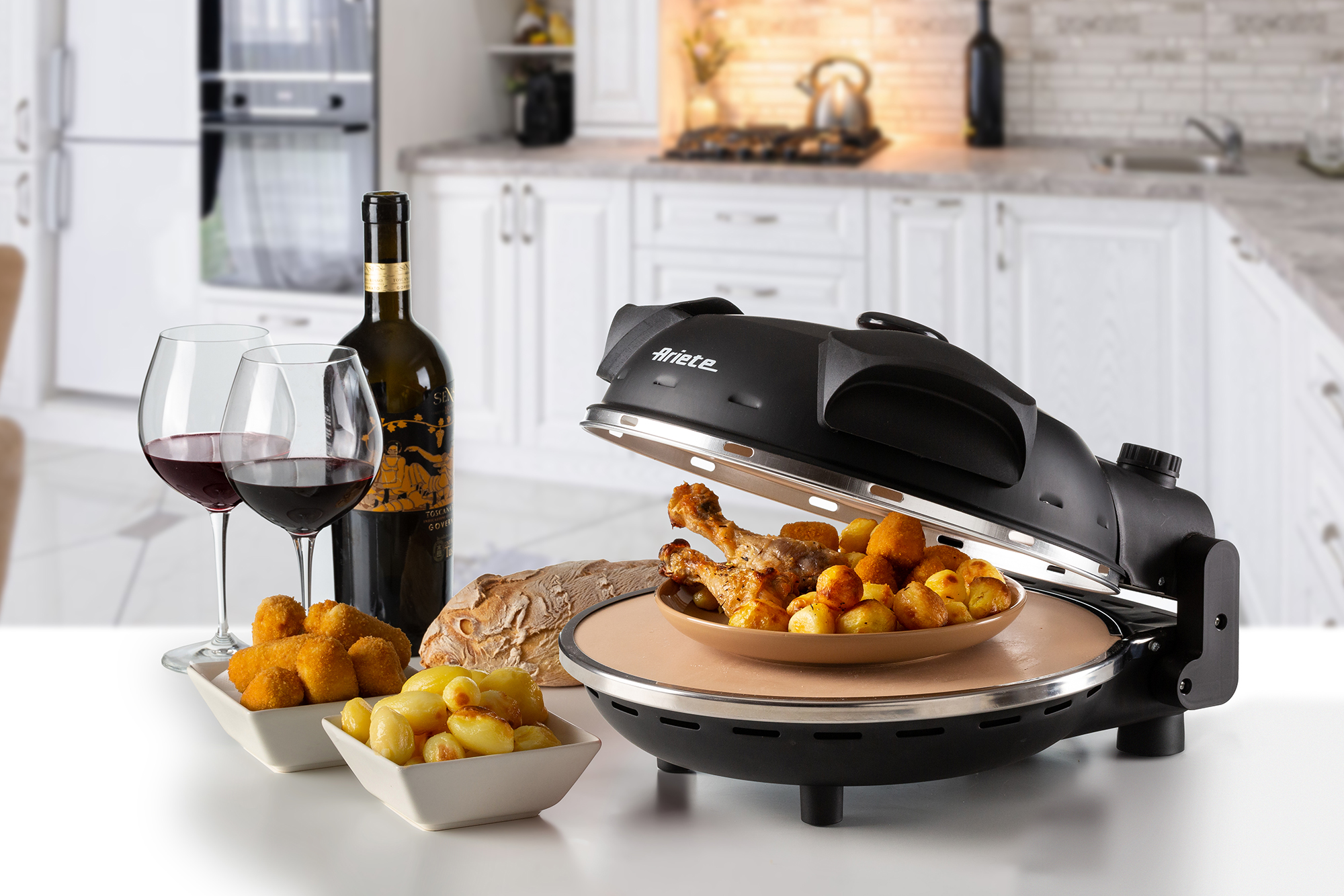 Une table avec de la nourriture, des verres à vin et un four à pizza dans un cadre de cuisine.
