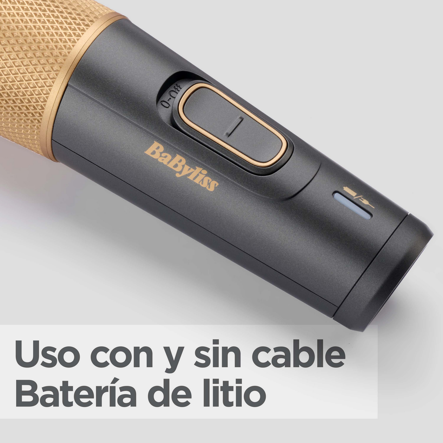 Primer plano de una herramienta de peinado con parte superior dorada y cuerpo gris. El texto está en español.