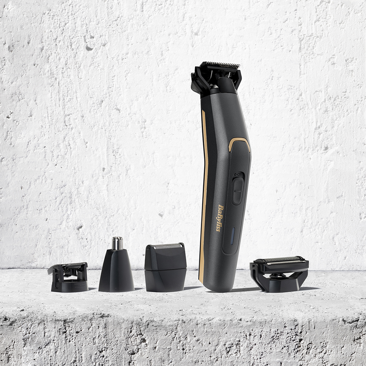 Recortadora de barba Babyliss negra y dorada con accesorios sobre superficie texturizada.