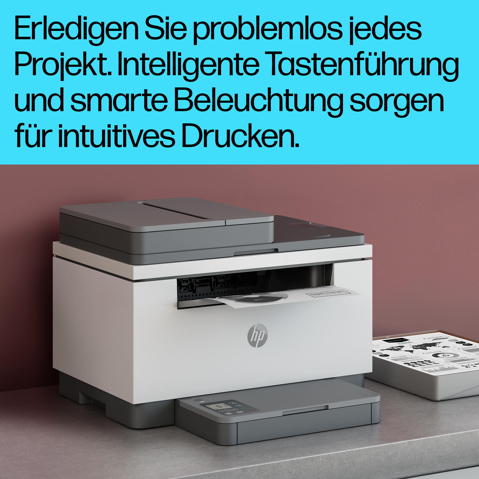 Ein weißer und grauer HP-Drucker auf einem Schreibtisch mit deutschem Text und einem Monitor.