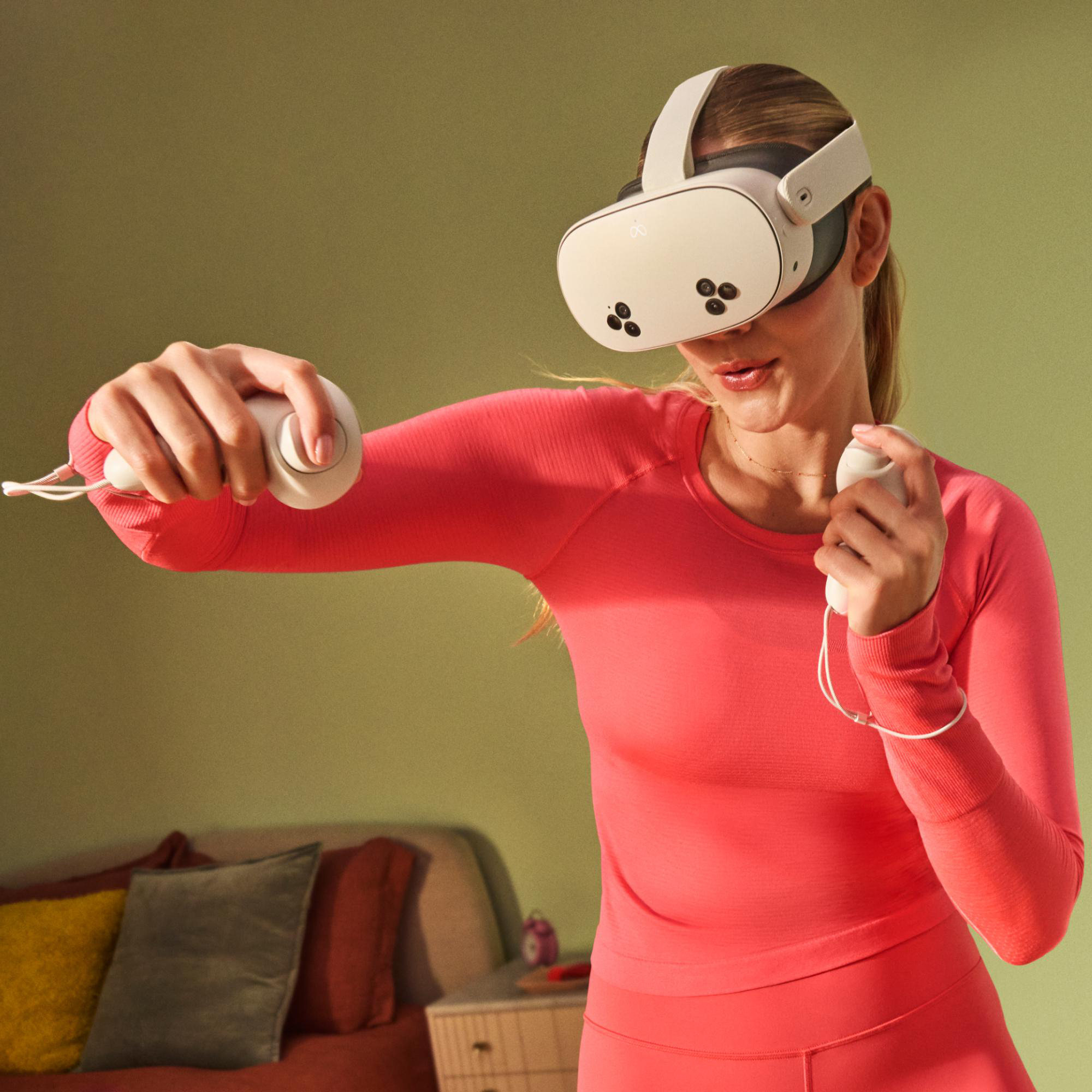 Frau mit VR-Headset und Controllern. Sie trägt ein pinkes Outfit.