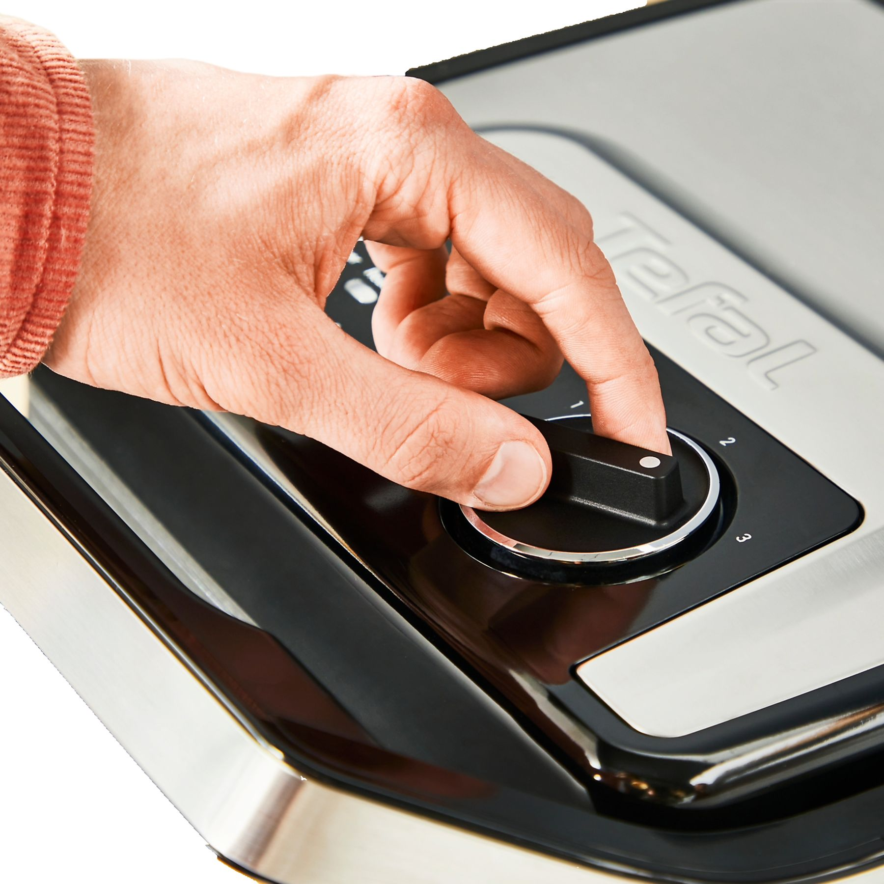 Egy kéz forgatja a tárcsát egy Tefal grillen, rajta 1, 2, 3 számokkal.