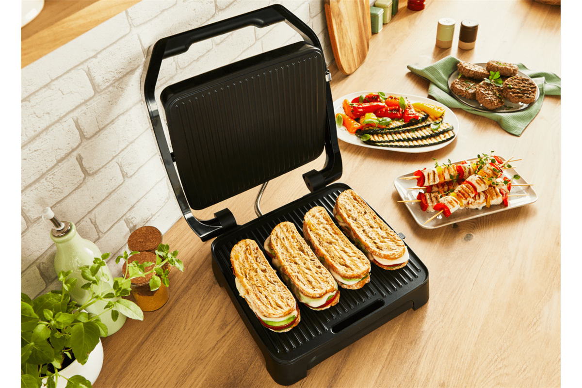 Grill szendvicsekkel, grillezett zöldségekkel és nyársakkal a faasztalon.
