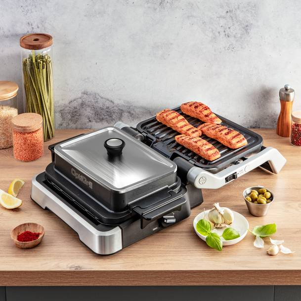 Egy OptiGrill grillezett lazaccal, fokhagymával, olajbogyóval és fűszerekkel a faasztalon.