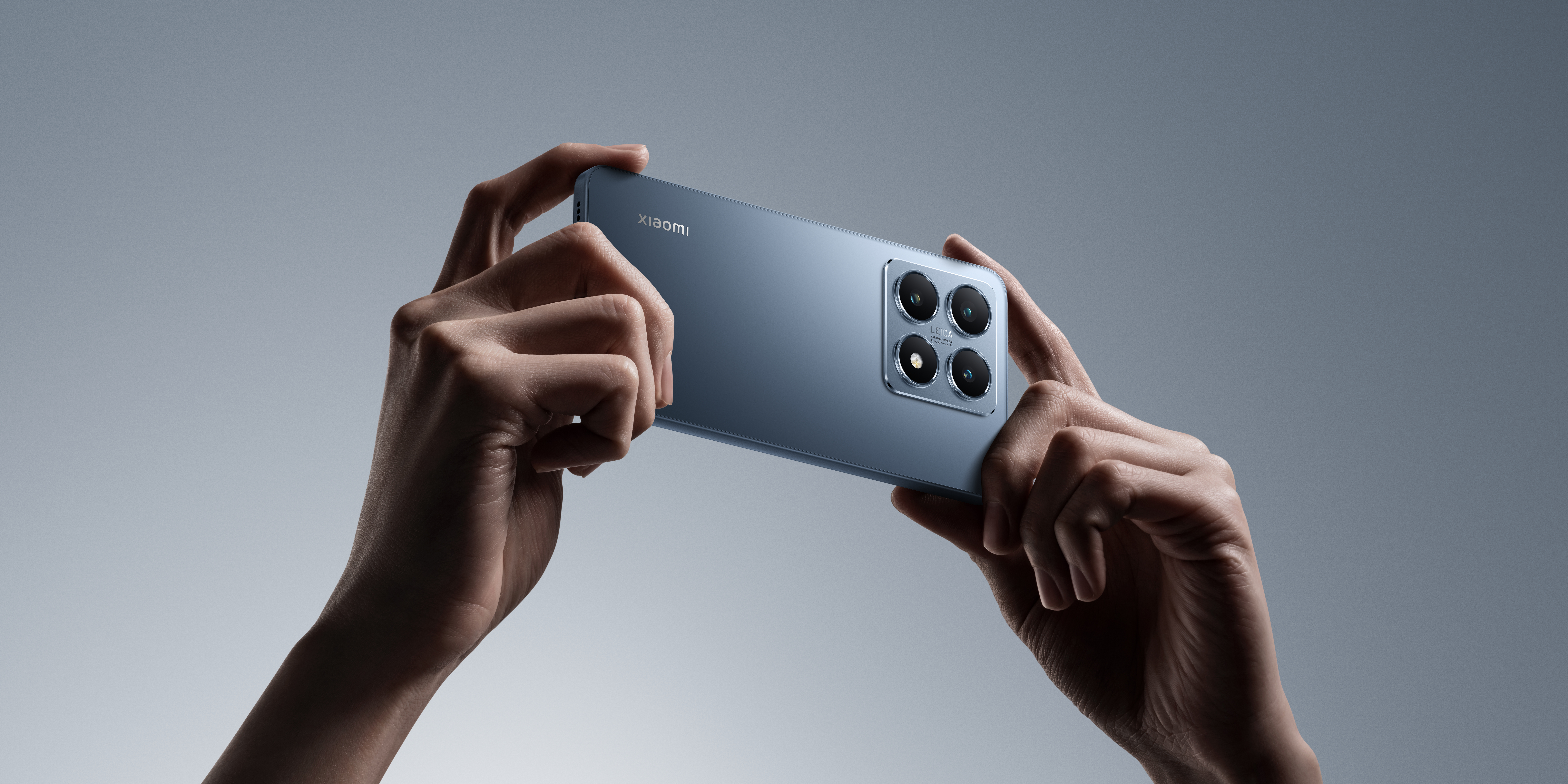 Hände halten ein blaues Smartphone. Die Rückseite des Telefons hat Kameras.
