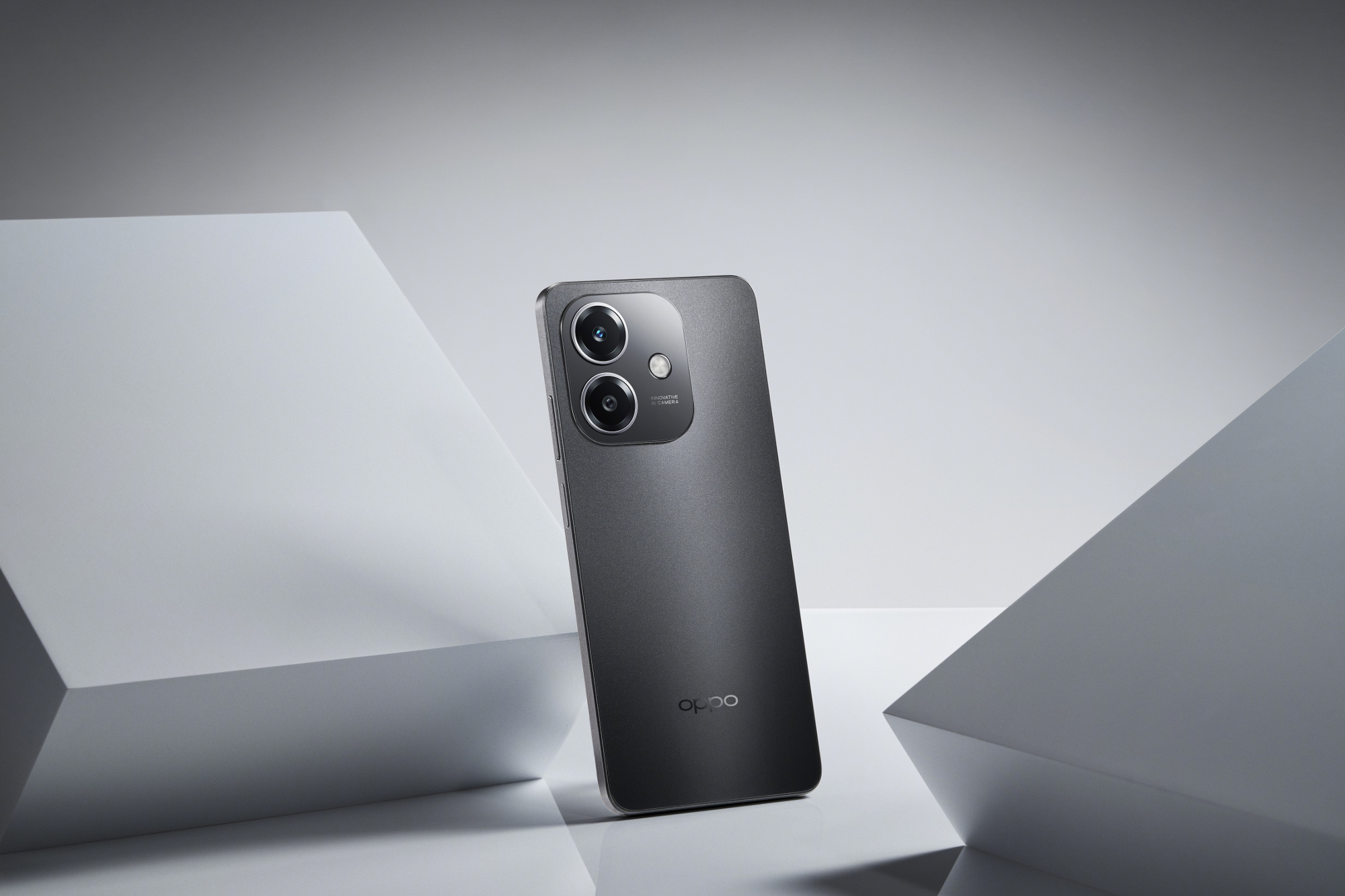 Ciemnoszary smartfon z dwoma aparatami i logo. Białe tło i geometryczne kształty.