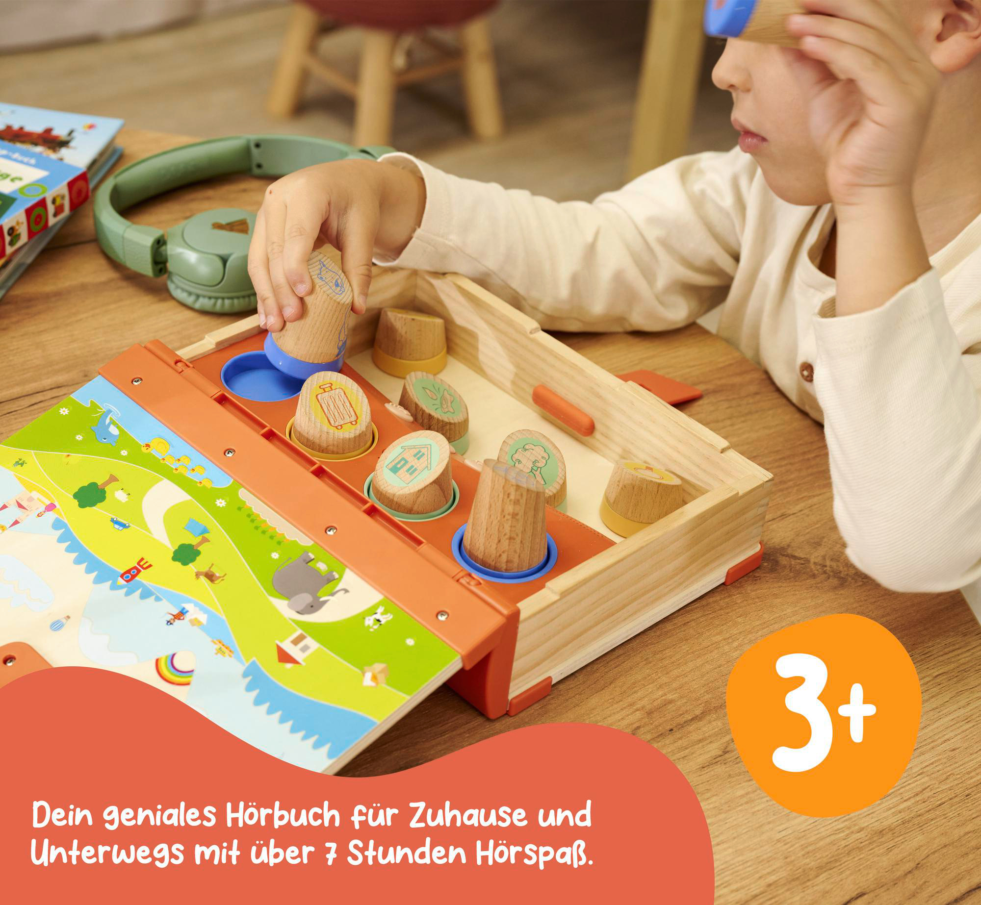 Ein Kind spielt mit einem Holzspielzeug, daneben ein Buch und Kopfhörer. Text: 'Dein geniales Hörbuch'.