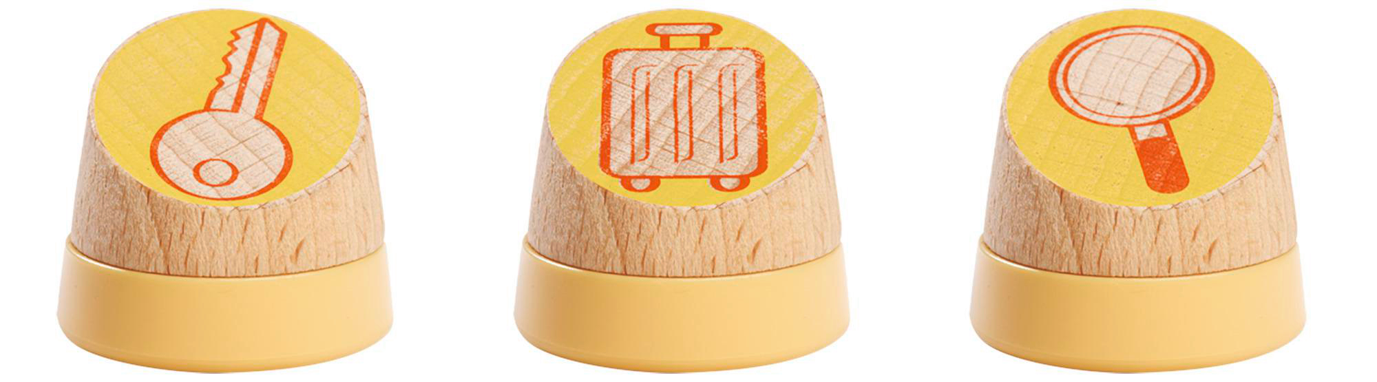 Drei Holzstempel mit gelben Sockeln, jeder mit einem anderen Reise-Symbol in Orange.