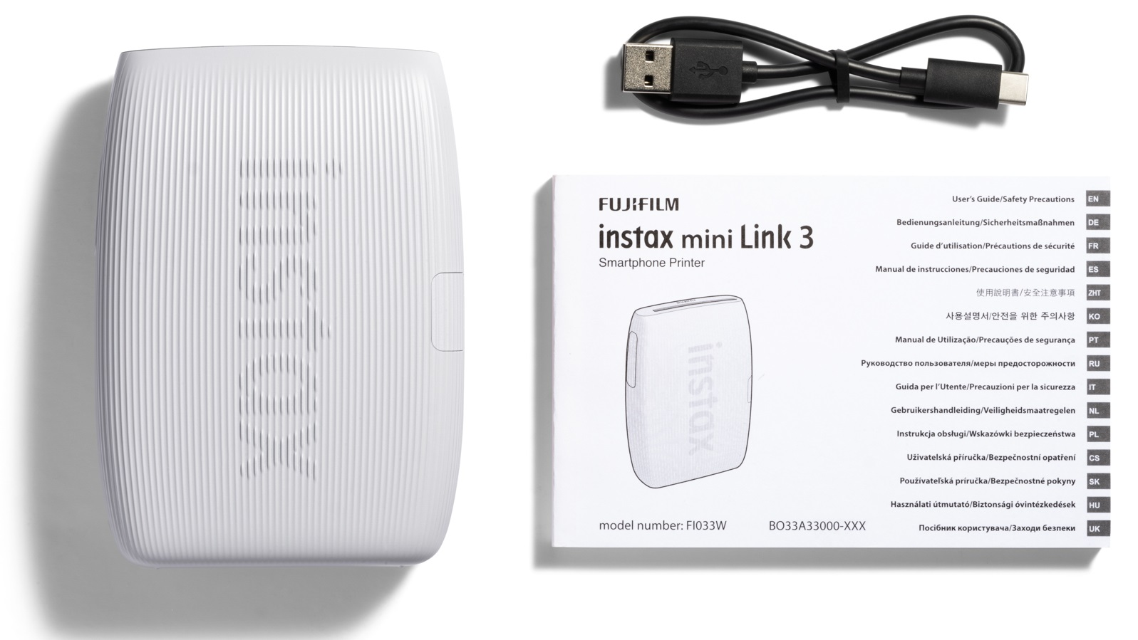Biała drukarka, kabel USB i instrukcja. Drukarka Instax mini Link 3 i kabel USB.