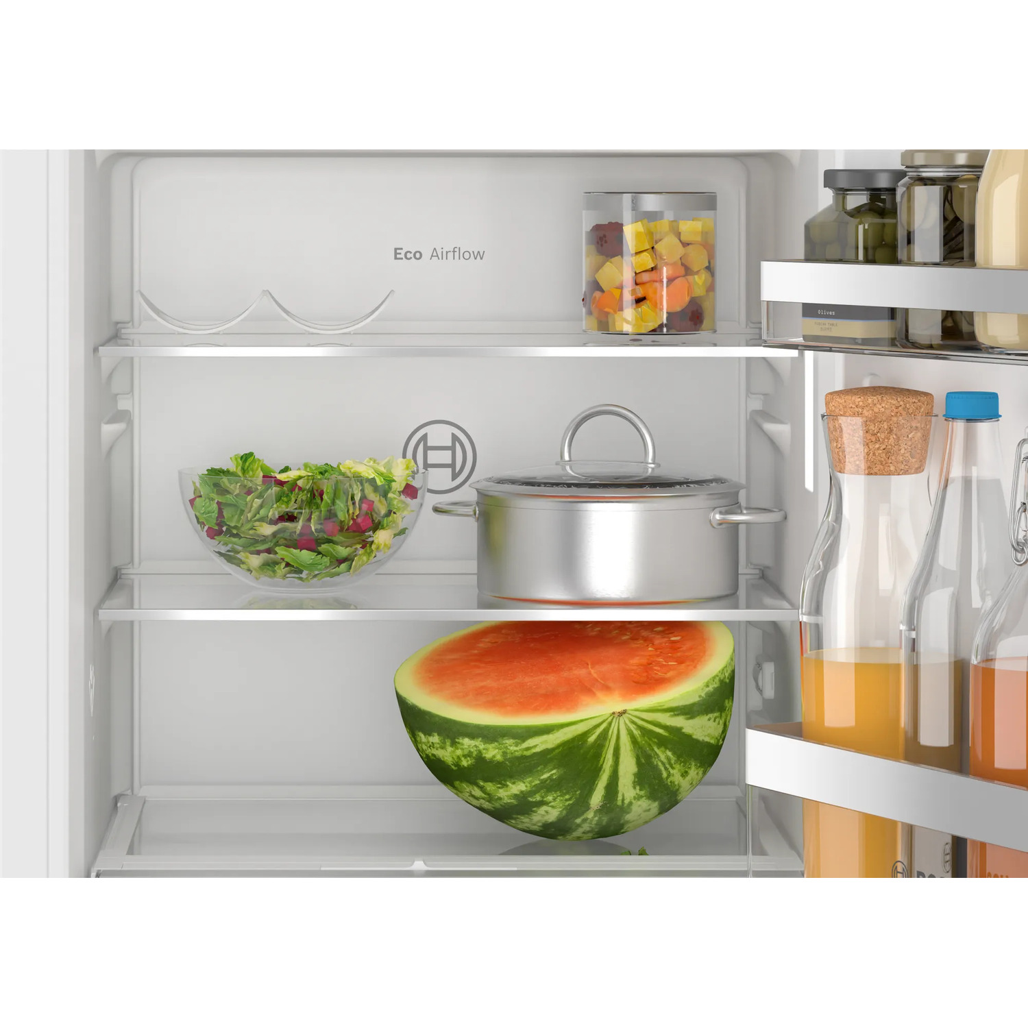 Interieur van koelkast met watermeloen, salade, pot en potten.