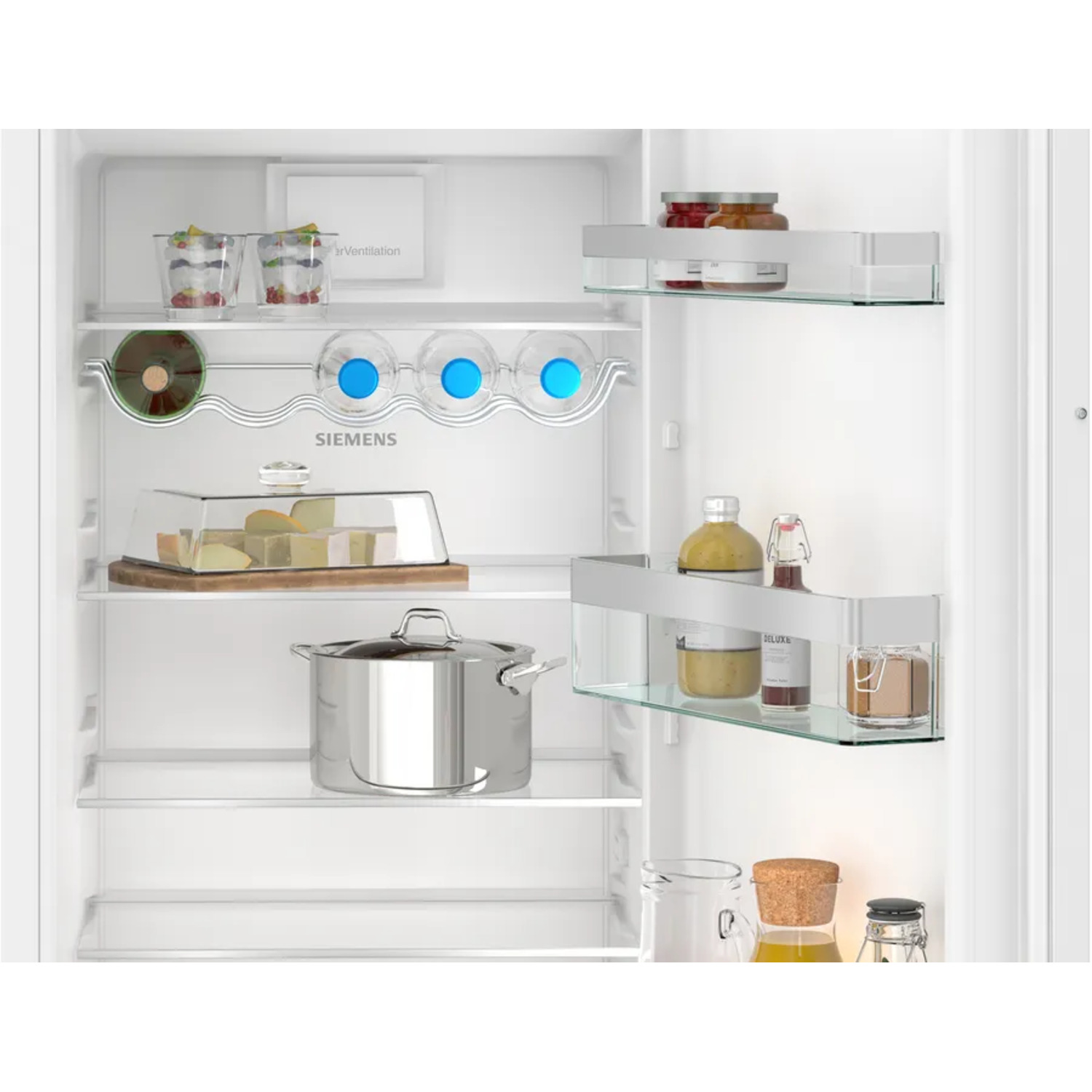 À l'intérieur d'un réfrigérateur blanc, rempli d'aliments sur des étagères en verre.