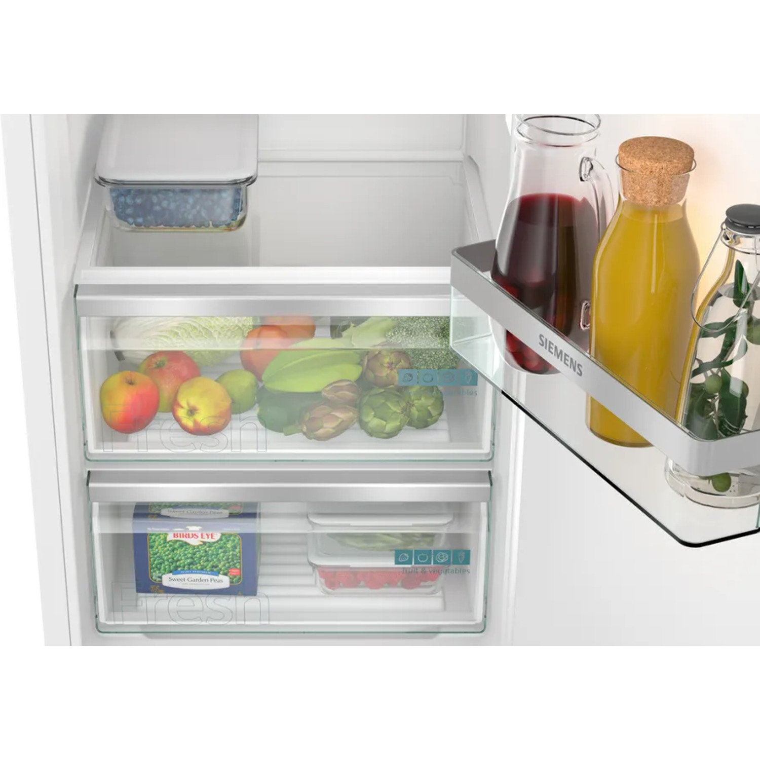 Intérieur de réfrigérateur avec étagères en verre, tiroirs avec fruits et légumes, et bouteilles de jus.
