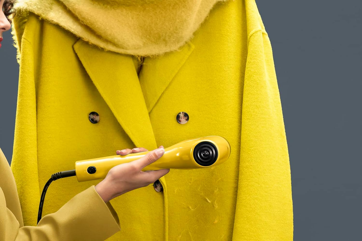 Une personne repassant un manteau jaune avec un défroisseur jaune.