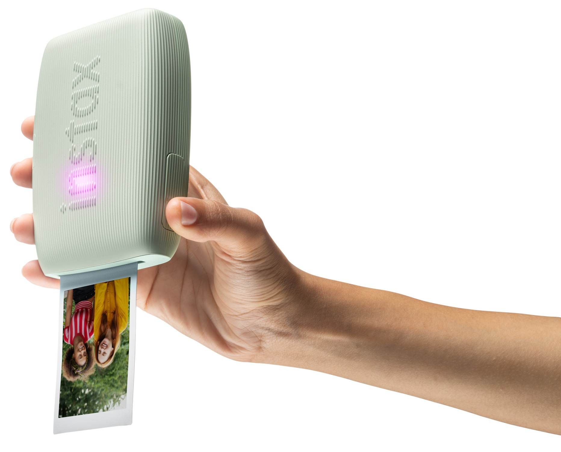 Ręka trzymająca zieloną drukarkę Instax z drukowanym zdjęciem.