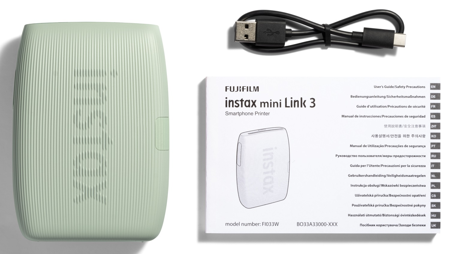 Jasnozielona drukarka, kabel i instrukcja na białej powierzchni. Drukarka jest mała.