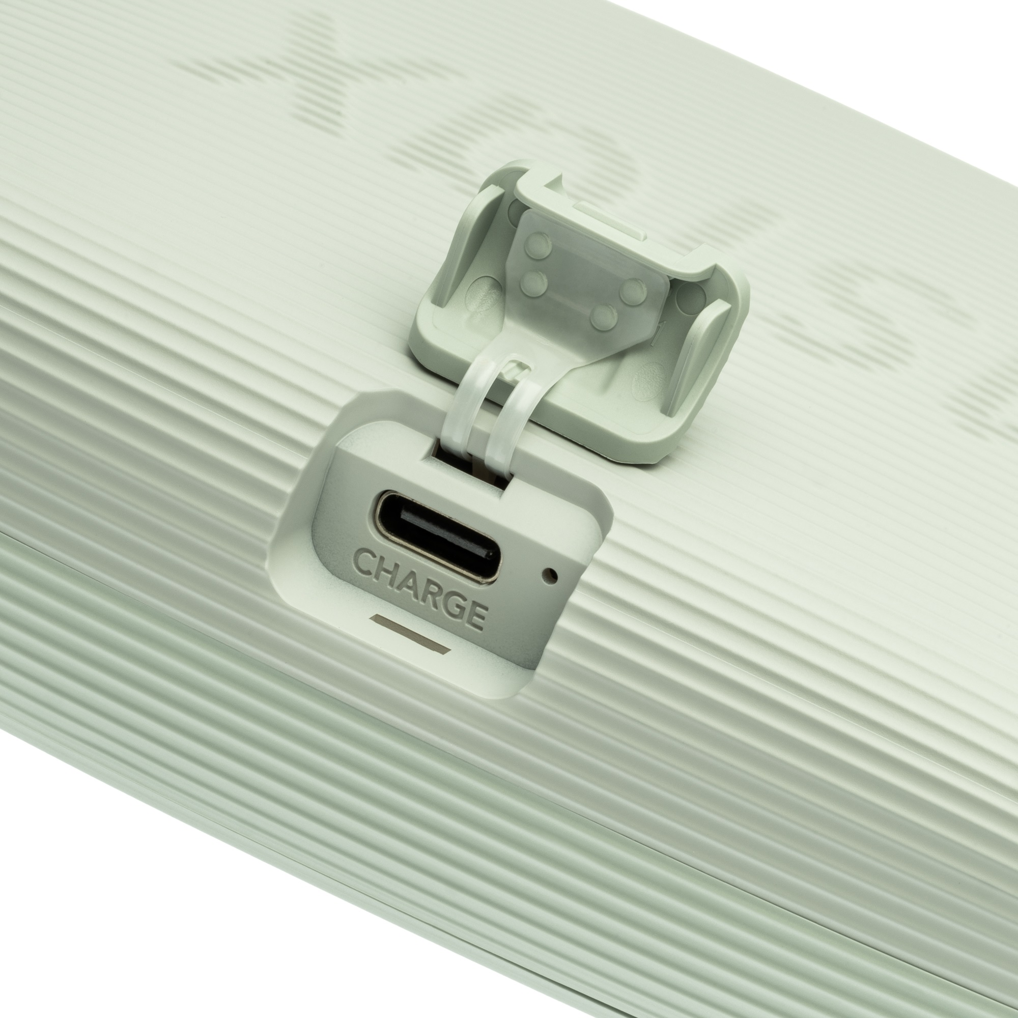 Zbliżenie portu ładowania białego urządzenia. Widoczny tekst CHARGE. Białe tło.