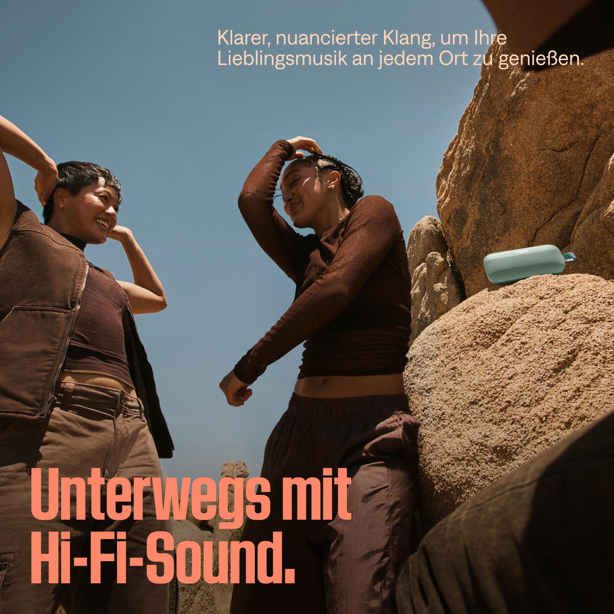 Zwei Frauen tanzen in der Nähe von Felsen, im Hintergrund ein Lautsprecher.