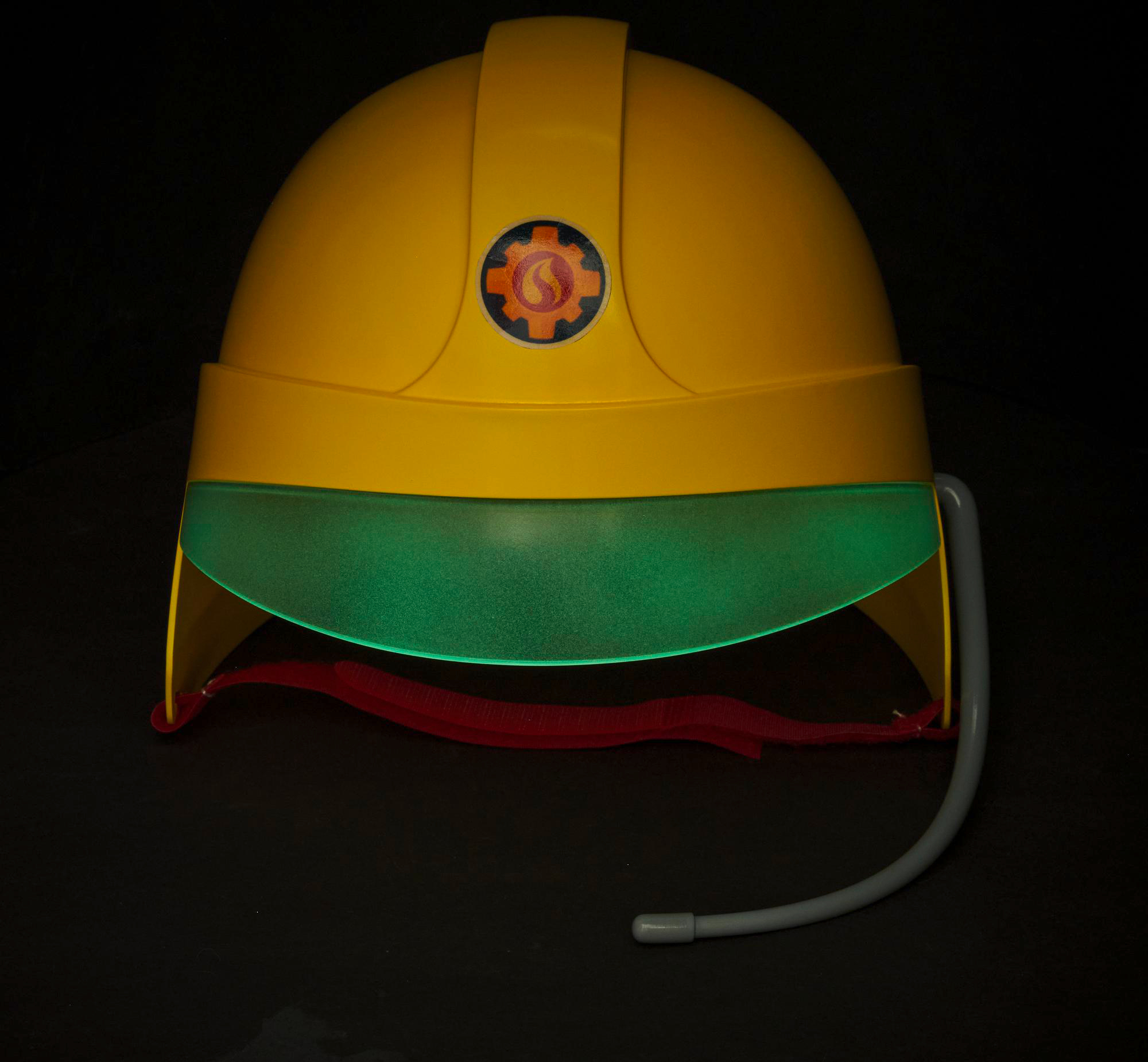 Gelber Schutzhelm mit grünem Visier. Das Visier ist beleuchtet. Der Hintergrund ist schwarz.