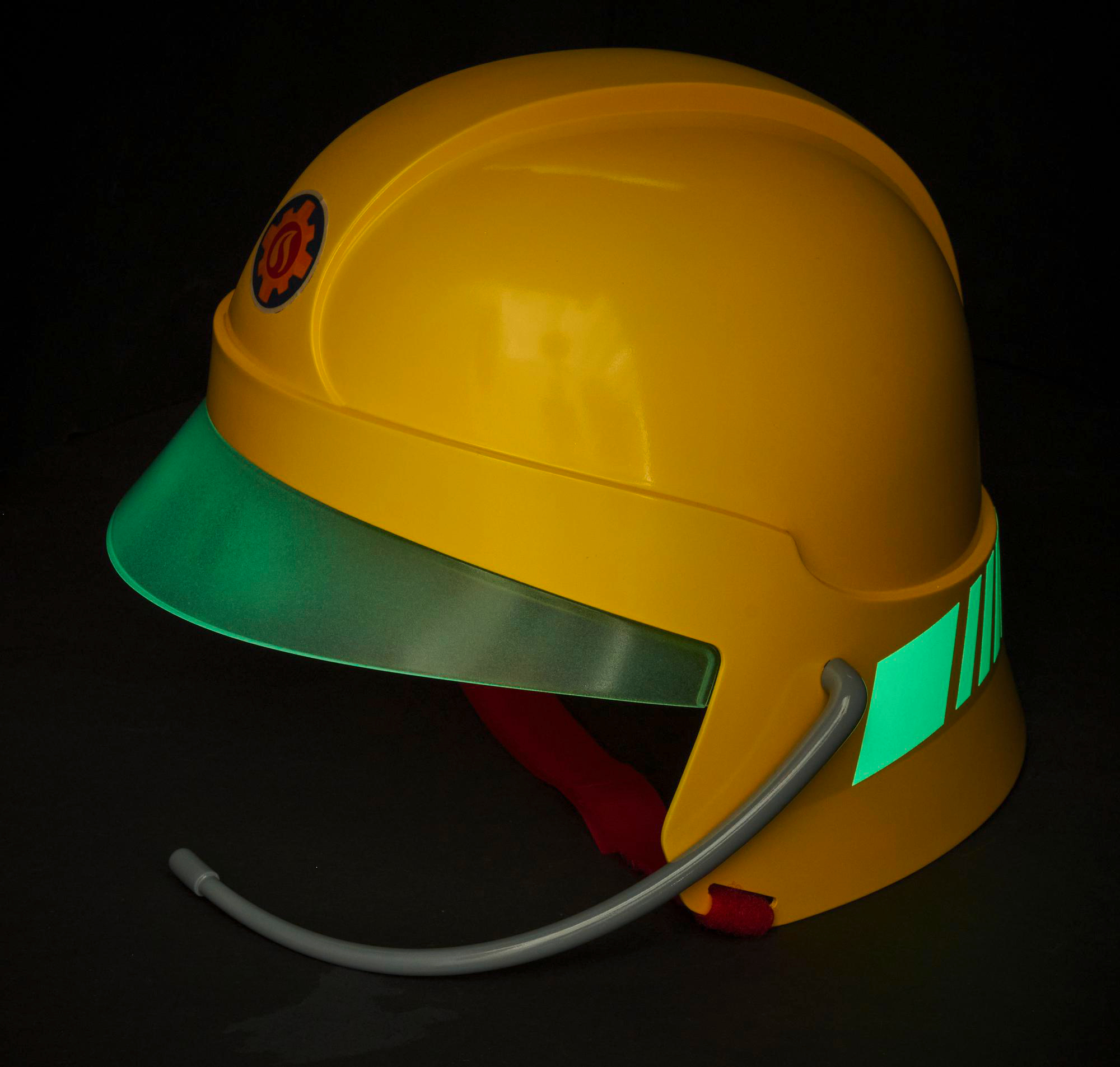 Ein gelber Feuerwehrhelm mit grünem Visier und reflektierenden Streifen. Dunkler Hintergrund.