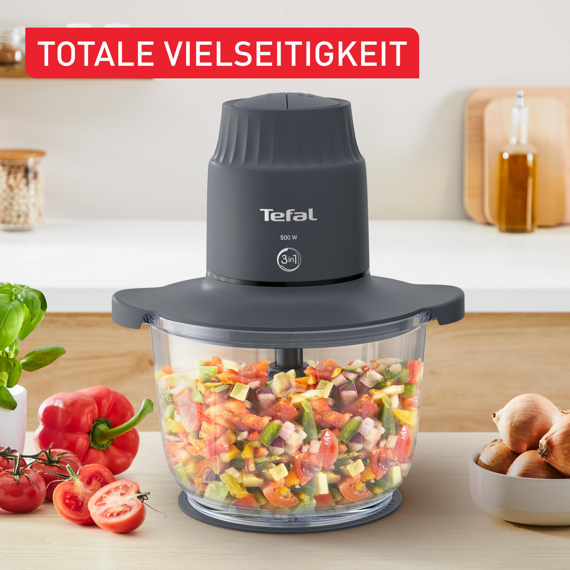 Eine Küchenmaschine mit gehacktem Gemüse. Text: 'TOTALE VIELSEITIGKEIT' und der Markenname 'Tefal'.