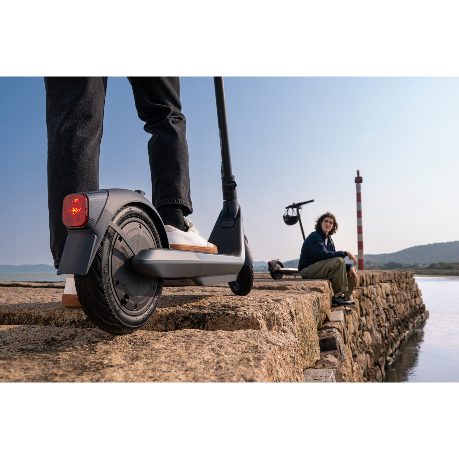 Personne sur un scooter sur une jetée. Une autre personne est assise.